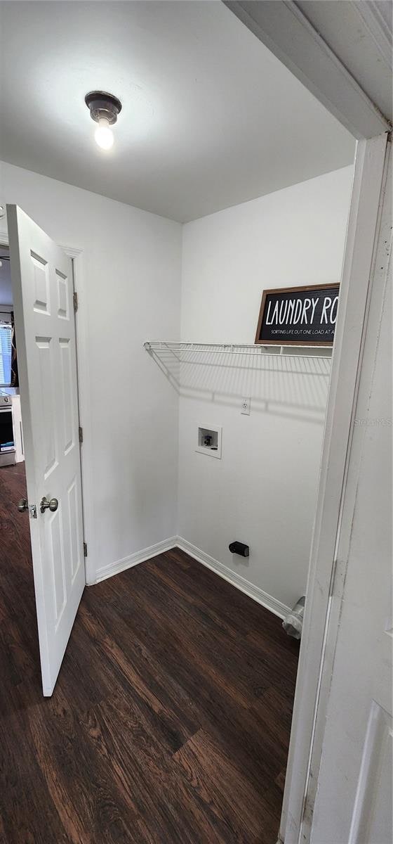 clothes washing area with dark wood-type flooring and hookup for a washing machine