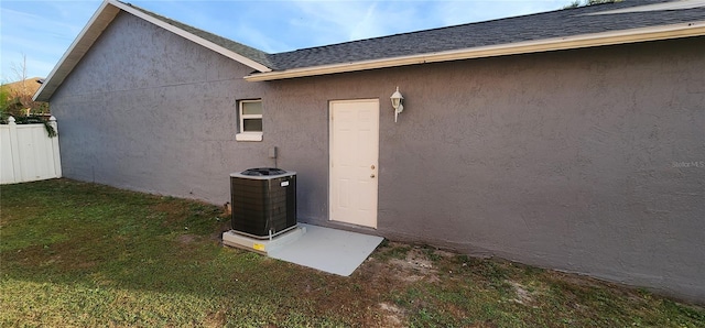 view of exterior entry featuring a yard and central air condition unit