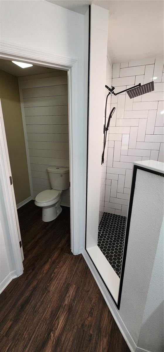 bathroom with a tile shower, hardwood / wood-style floors, and toilet