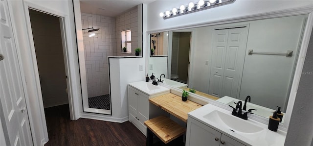 bathroom featuring hardwood / wood-style flooring, toilet, vanity, and tiled shower