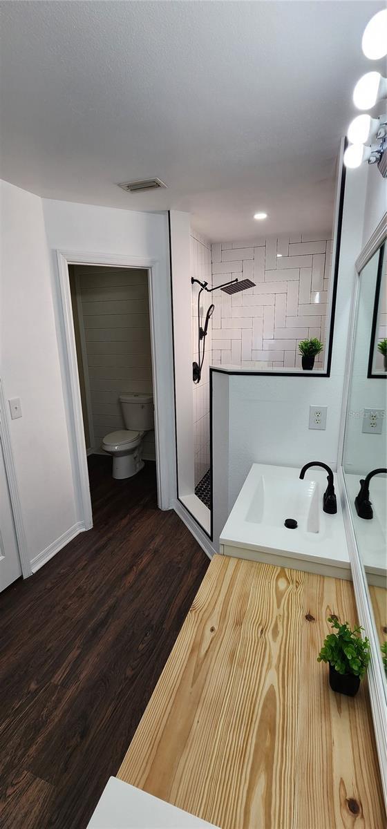 bathroom with hardwood / wood-style flooring, sink, toilet, and a shower