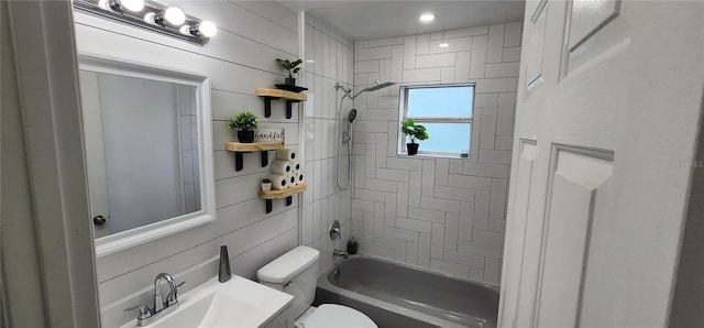 full bathroom featuring vanity, toilet, tiled shower / bath, and wooden walls