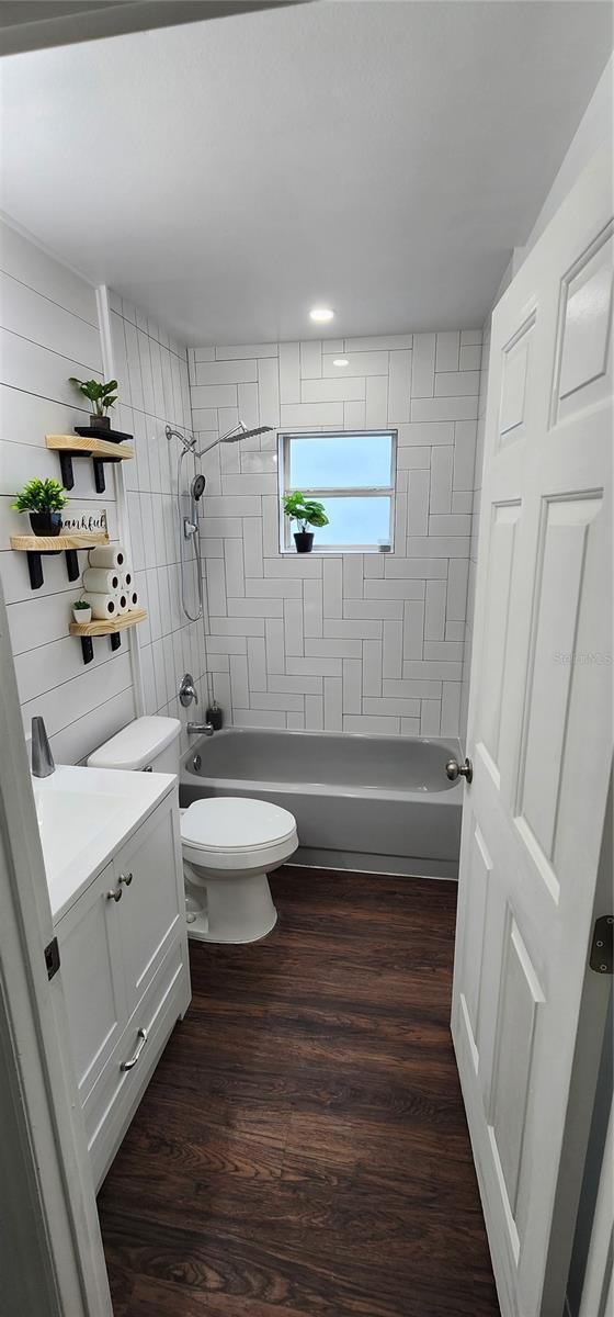 full bathroom featuring vanity, wood-type flooring, tiled shower / bath combo, and toilet