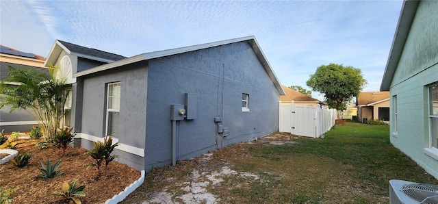 view of side of home with a lawn and central AC