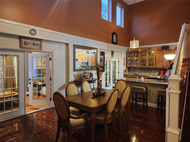 dining room featuring dark hardwood / wood-style floors, indoor wet bar, a high ceiling, and french doors