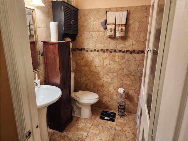 bathroom featuring toilet, tile walls, and sink