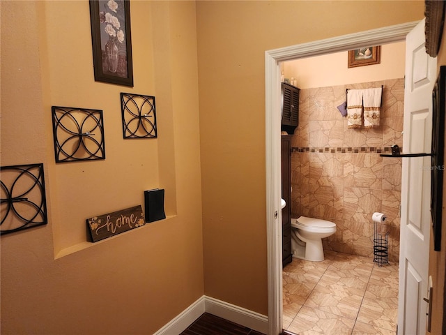 bathroom with toilet and tile walls