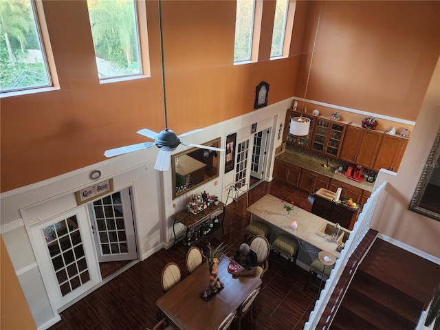 living room with a towering ceiling, a wealth of natural light, and ceiling fan