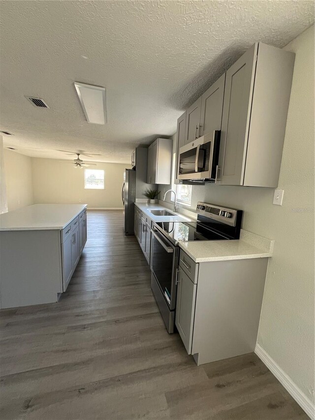 kitchen featuring sink, light wood-type flooring, a textured ceiling, and appliances with stainless steel finishes