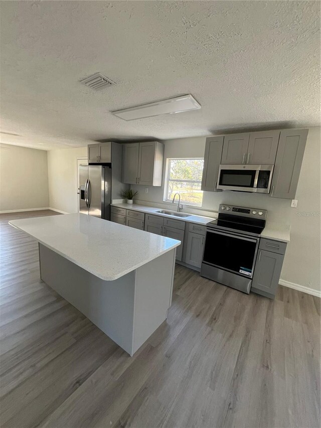 kitchen featuring stainless steel appliances, gray cabinets, and sink