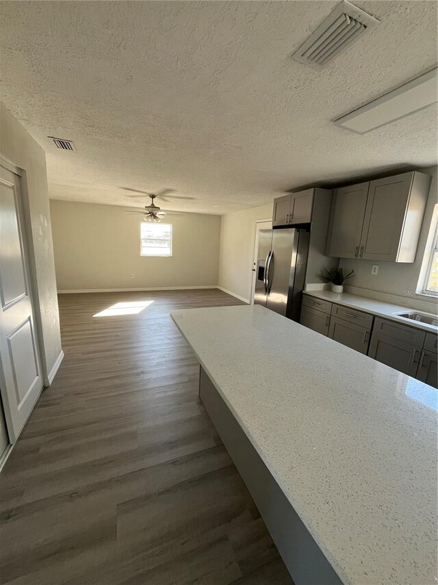 kitchen with gray cabinetry, plenty of natural light, stainless steel fridge, and dark hardwood / wood-style flooring