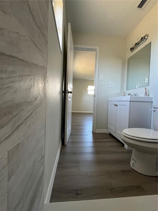 bathroom featuring wood-type flooring, vanity, a textured ceiling, and toilet