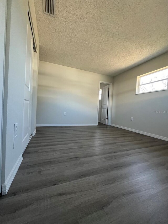 spare room featuring dark hardwood / wood-style flooring and a textured ceiling