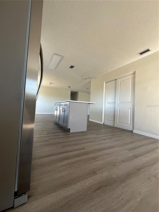 kitchen featuring dark hardwood / wood-style floors, a textured ceiling, and stainless steel refrigerator