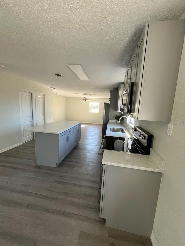 kitchen with ceiling fan, sink, dark wood-type flooring, and a textured ceiling