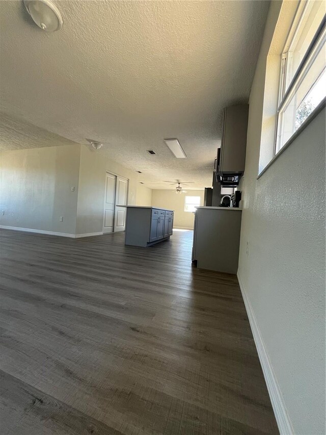 unfurnished living room with a textured ceiling and dark wood-type flooring