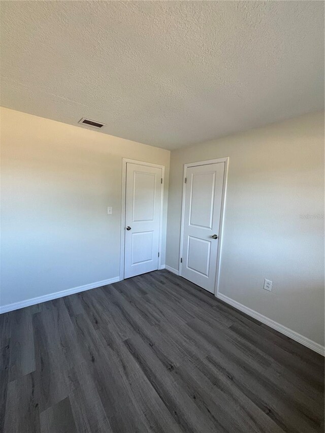 spare room featuring a textured ceiling and dark hardwood / wood-style floors