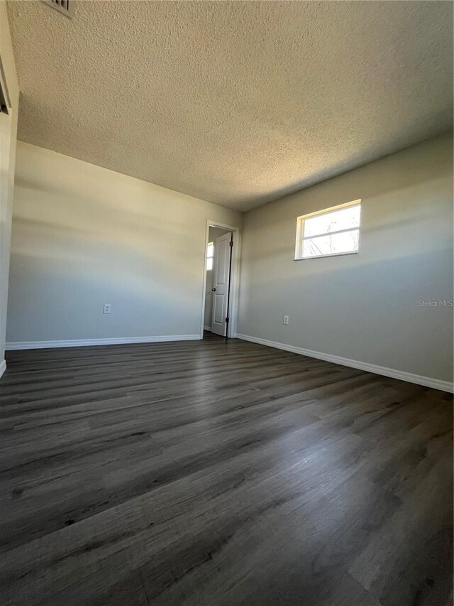 unfurnished room featuring dark hardwood / wood-style flooring and a textured ceiling