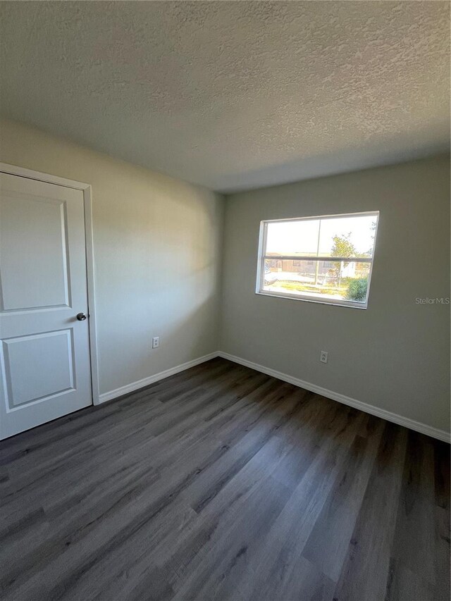 empty room featuring dark hardwood / wood-style floors and a textured ceiling