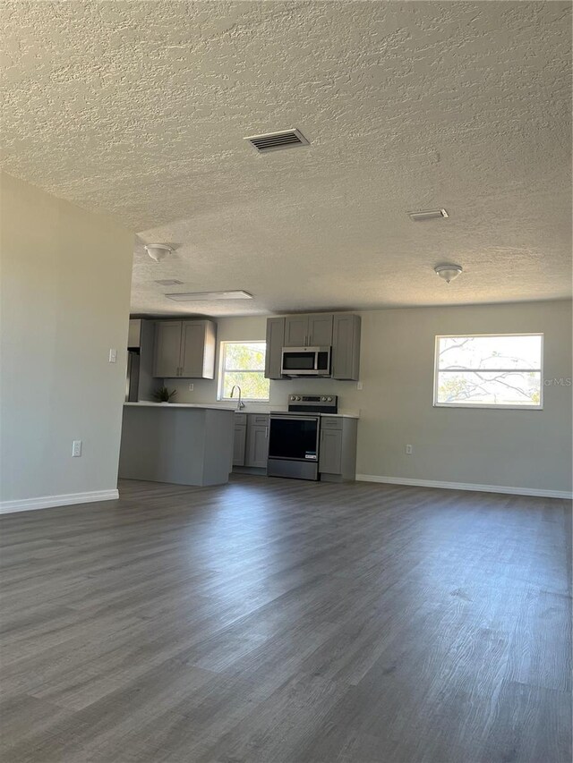 unfurnished living room featuring dark hardwood / wood-style flooring, a textured ceiling, and sink