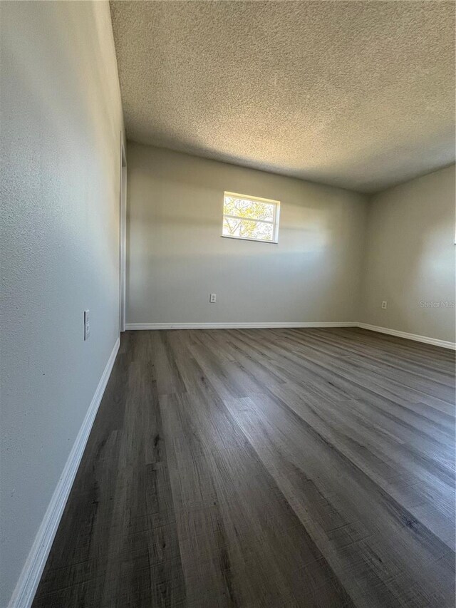 spare room with a textured ceiling and dark hardwood / wood-style floors