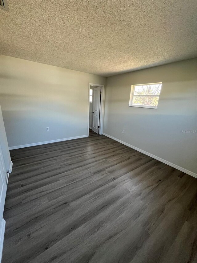 empty room featuring a textured ceiling and dark hardwood / wood-style floors