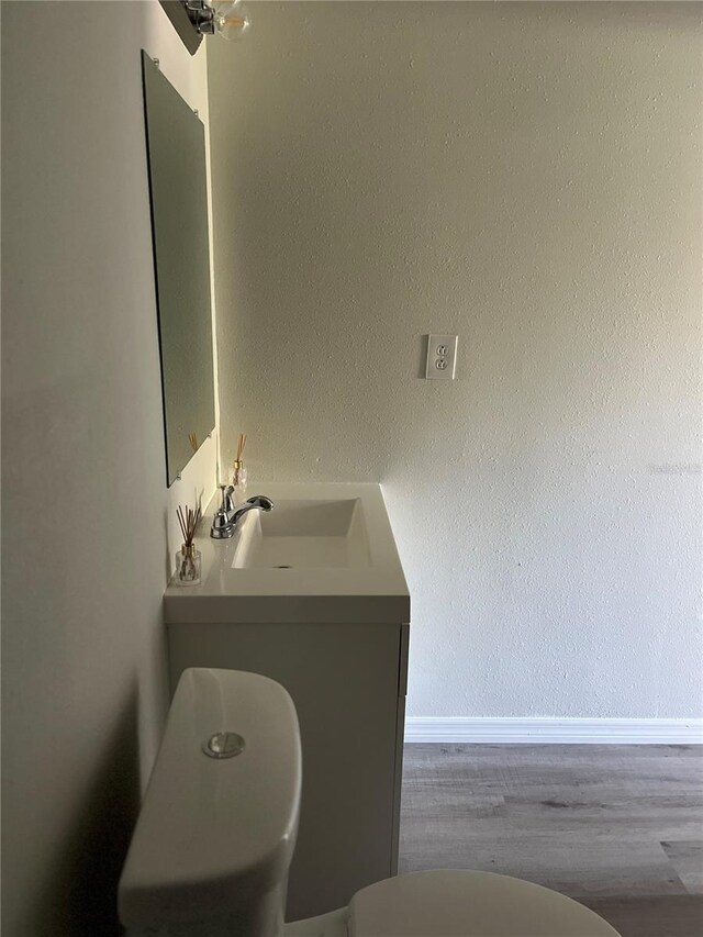 bathroom featuring wood-type flooring, vanity, and toilet