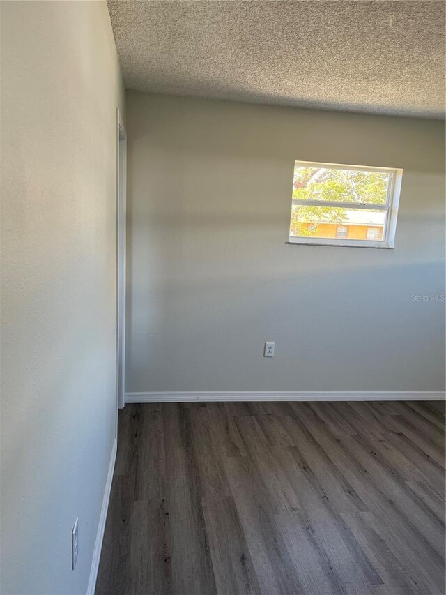 unfurnished room with dark hardwood / wood-style flooring and a textured ceiling