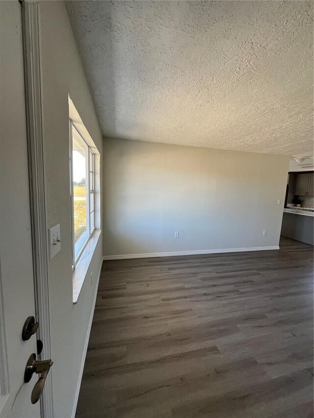 spare room with dark wood-type flooring and a textured ceiling