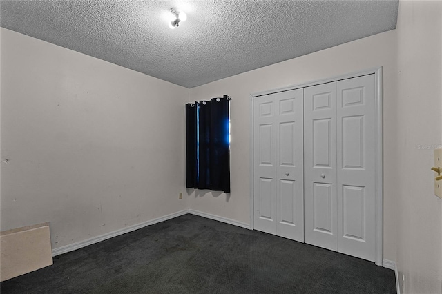 unfurnished bedroom with dark colored carpet, a textured ceiling, and a closet