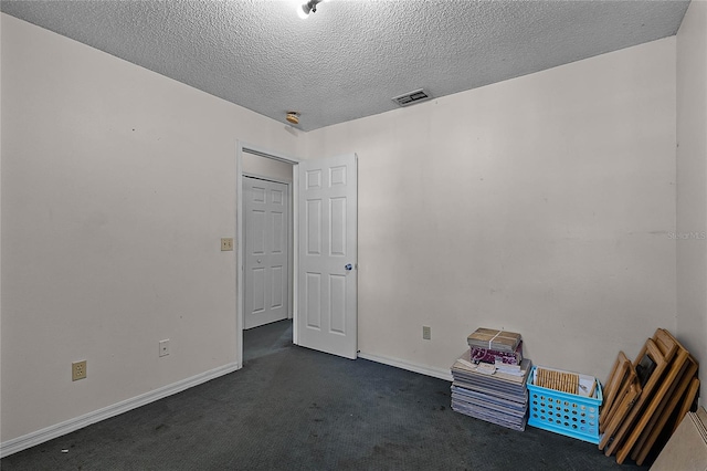 unfurnished room featuring a textured ceiling and dark carpet