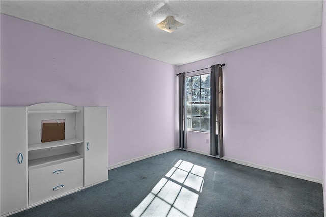 spare room with dark carpet and a textured ceiling