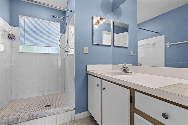 bathroom with a tile shower, tile patterned floors, and vanity