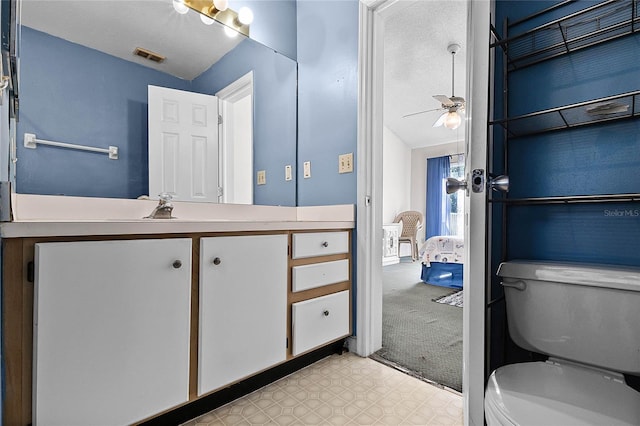 bathroom with vanity, toilet, ceiling fan, and vaulted ceiling