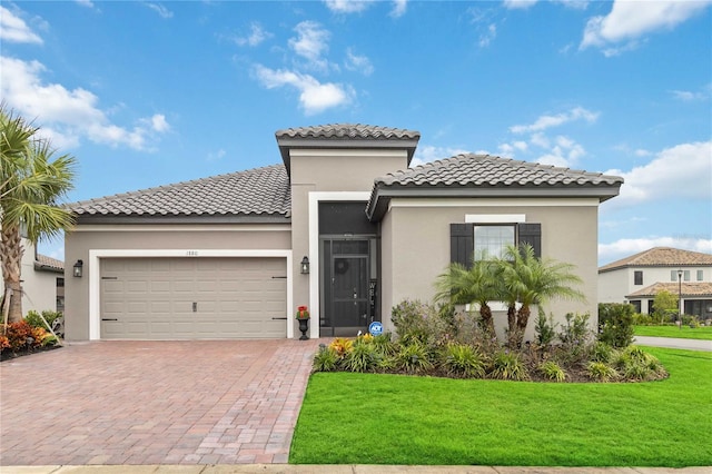 mediterranean / spanish-style house with a garage and a front lawn