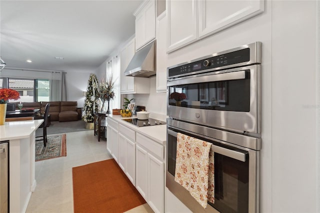 kitchen with ventilation hood, white cabinets, stainless steel double oven, and black electric stovetop