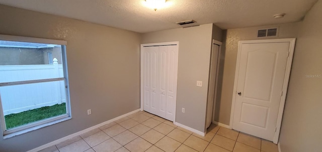 unfurnished bedroom with a closet, light tile patterned floors, and a textured ceiling