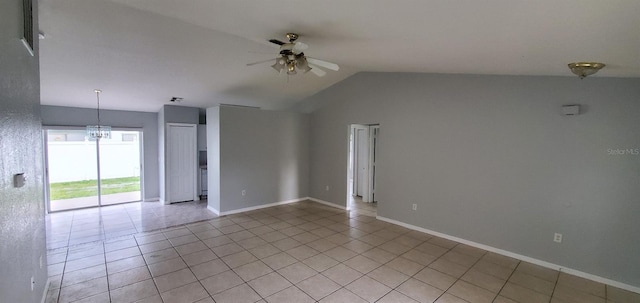 spare room featuring ceiling fan with notable chandelier, light tile patterned flooring, and vaulted ceiling