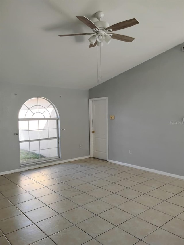 empty room with ceiling fan, light tile patterned floors, and vaulted ceiling