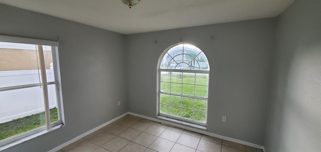 spare room with light tile patterned floors and a wealth of natural light