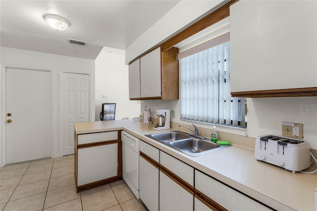 kitchen featuring white dishwasher, kitchen peninsula, sink, light tile patterned floors, and white cabinetry