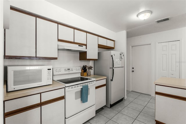 kitchen featuring white cabinetry, light tile patterned flooring, and white appliances