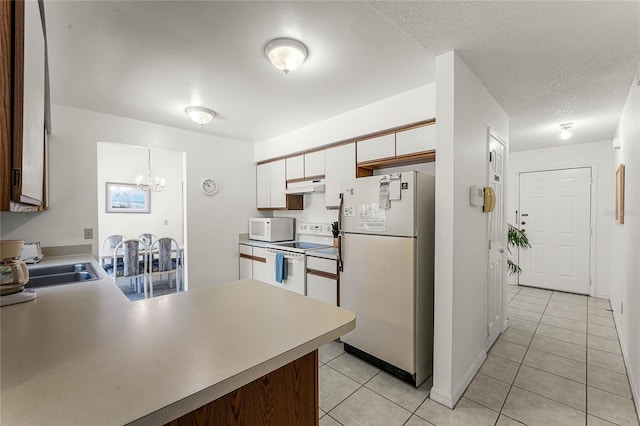 kitchen featuring white cabinetry, light tile patterned flooring, white appliances, and a textured ceiling