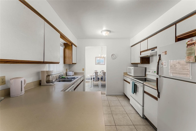 kitchen with white appliances, white cabinets, sink, light tile patterned floors, and a chandelier