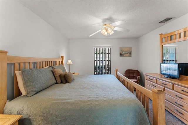 carpeted bedroom with a textured ceiling, multiple windows, and ceiling fan