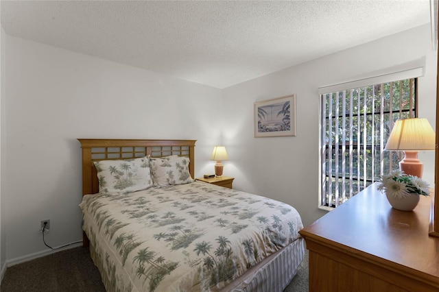 bedroom with dark colored carpet and a textured ceiling