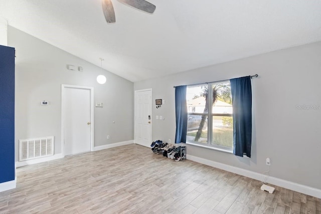 spare room with ceiling fan, vaulted ceiling, and light wood-type flooring