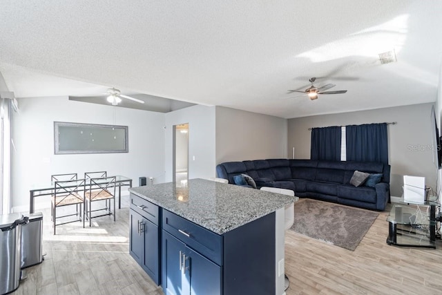 kitchen featuring blue cabinetry, a textured ceiling, and light hardwood / wood-style floors