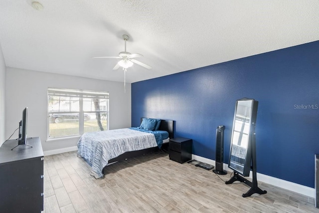 bedroom featuring ceiling fan, light wood-type flooring, and a textured ceiling