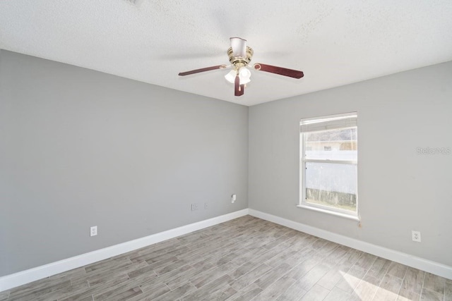 empty room with ceiling fan, light wood-type flooring, and a textured ceiling